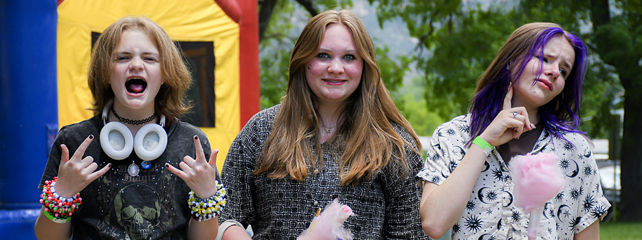 Three friends eat cotton candy and make faces at the camera