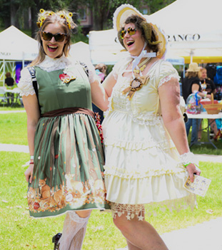 Two friends in flowered sundresses and hats pose for the camera